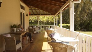 A covered porch with wicker furniture, a table, and chairs. - The Carriages (Pokolbin)