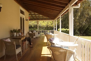 Un porche cubierto con muebles de mimbre, una mesa y sillas.