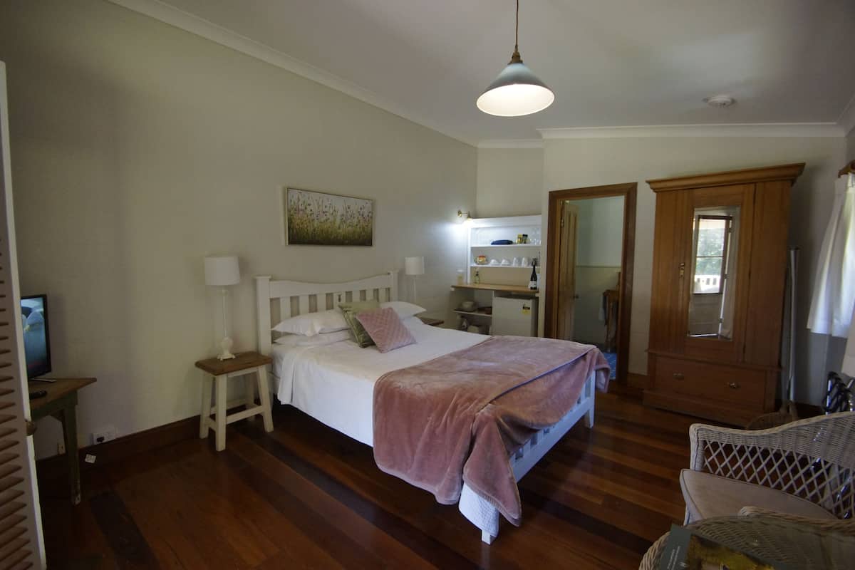 A bedroom with a bed, bedside table, lamp, and a wooden wardrobe.