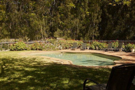 Una piscina al aire libre de temporada, sillones reclinables de piscina