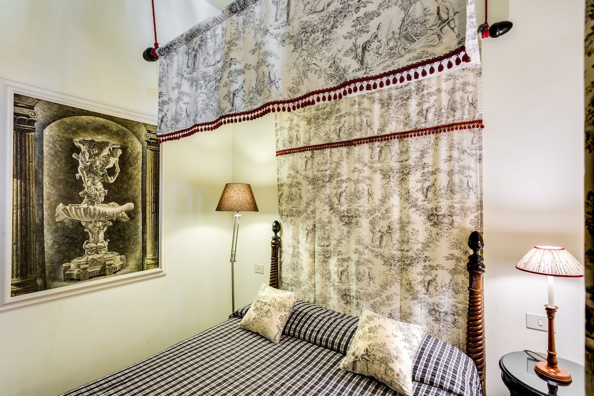 Ein Schlafzimmer mit einem Bett, einem Nachttisch, einer Lampe, einem Wandregal und einem gerahmten Kunstwerk.