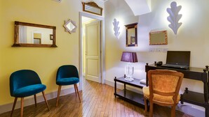 Une pièce avec un plancher en bois, un bureau avec un ordinateur portable, deux chaises, une lampe et des miroirs fixés au mur.