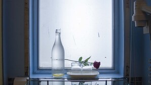 A bathroom with a window, a sink, and a bottle of water. - Franchise One Hotel (Makati)