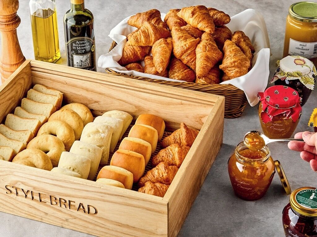 A wooden box labeled 'STYLE BREAD' containing various types of bread.