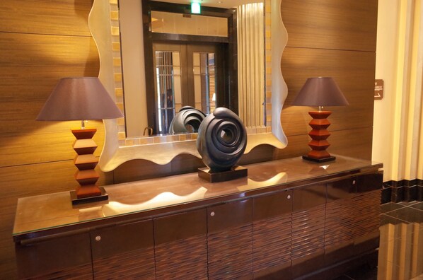 Une salle de bain moderne avec un meuble-lavabo en bois, deux lampes fixées au mur et un grand miroir.