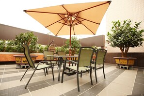An outdoor patio with tables and chairs, a large umbrella, and potted plants. - Beauty Hotels - Beautique Hotel (Taipei)