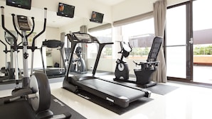 Een fitnessruimte met loopbanden, hometrainers en elliptische trainers.