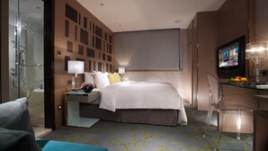 Een hotelkamer met een bed, een bureau, een televisie en een douche.