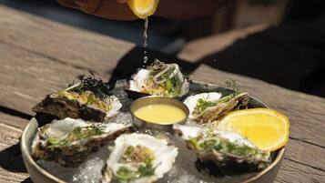 A bowl of oysters with a lemon half and a small bowl of sauce.