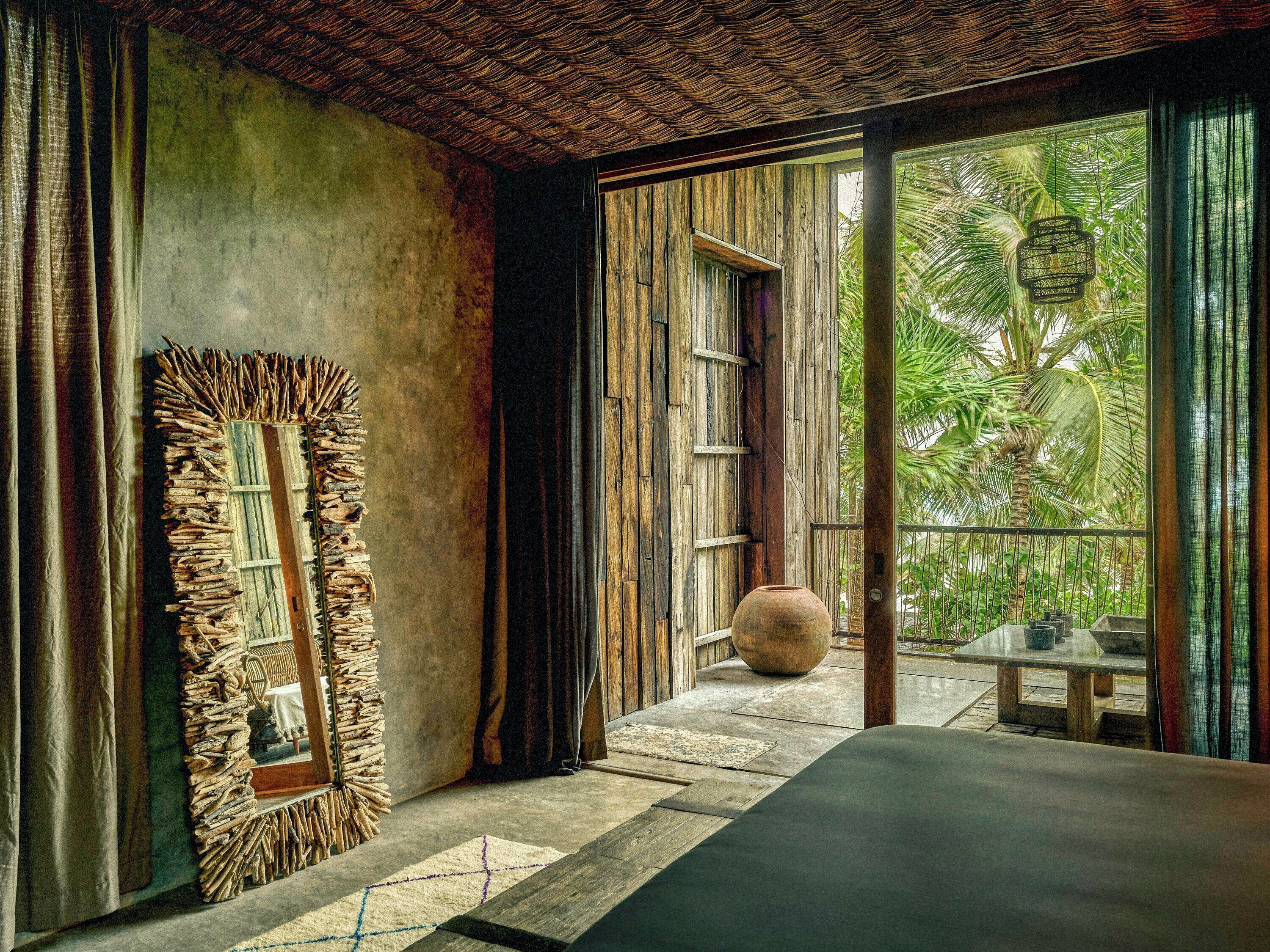 A room with a large mirror, a wooden ceiling, and a view of greenery outside.