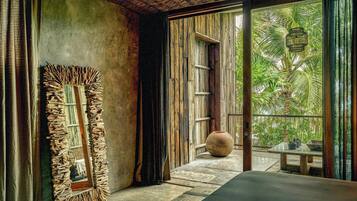 A room with a large mirror, a wooden ceiling, and a view of greenery outside.