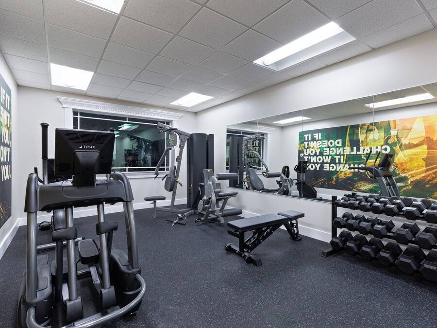 A gym with exercise equipment, mirrors, and motivational posters.