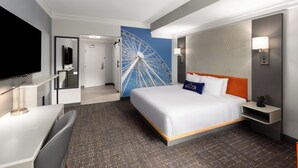 A hotel room with a bed, a TV, a desk, a wall-mounted lamp, and a large wall decoration. - The Walden, Trademark Collection By Wyndham (Pigeon Forge)