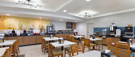 A modern cafe with multiple tables and chairs, a counter with various food and drink items, and a ceiling with recessed lighting.