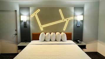 Ein Hotelzimmer mit einem großen Bett, einem Kopfteil mit geometrischem Lichtdesign, zwei Nachttischlampen und einem Telefon auf dem Nachttisch.