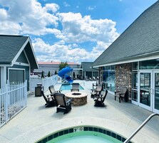 A pool area with lounge chairs, a hot tub, and a blue slide.