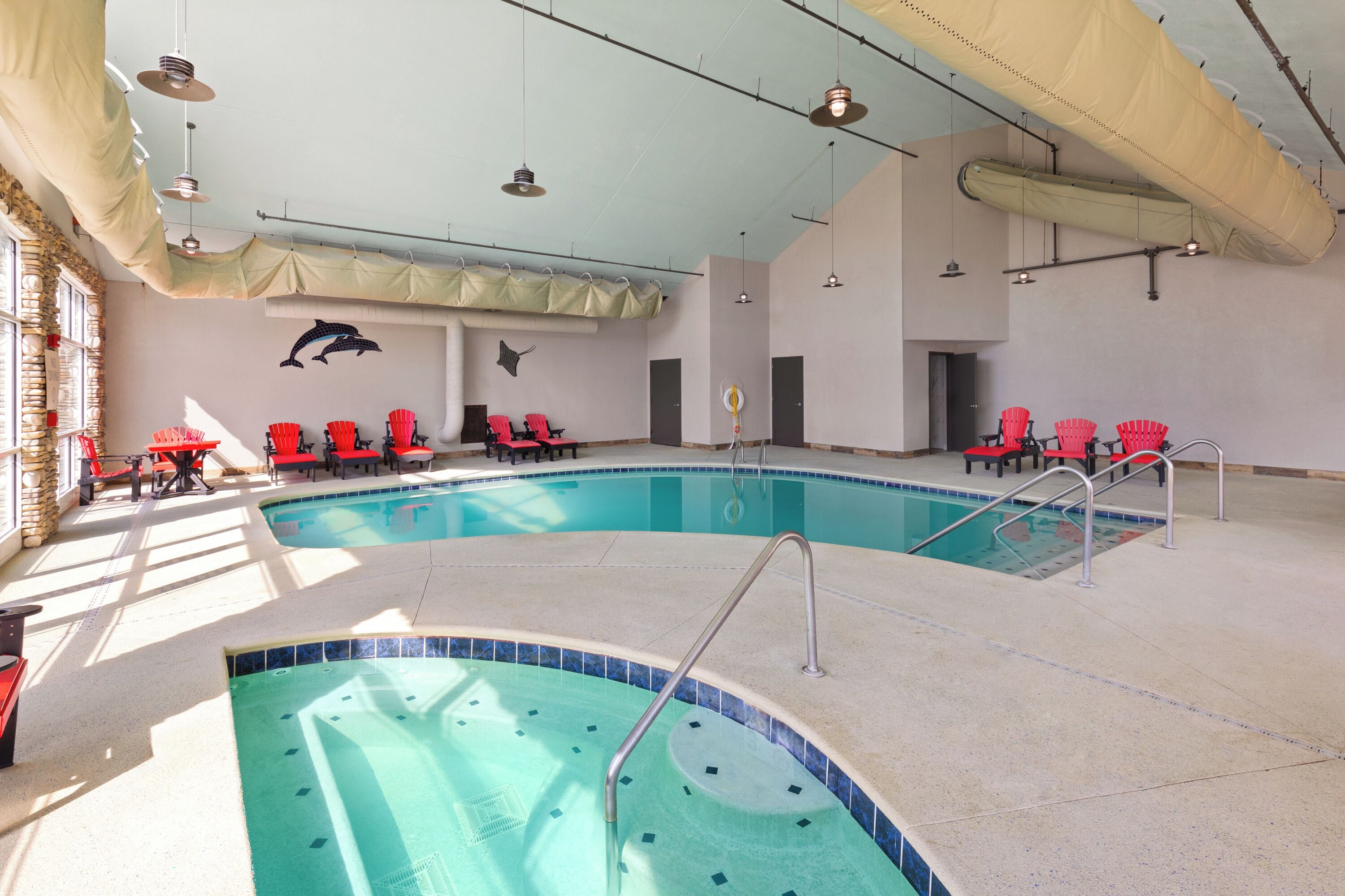 Ein Hallenbad mit mehreren Bahnen, roten Liegestühlen und einem Wandgemälde von einem Delfin.