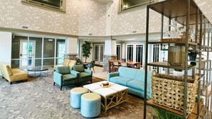 A spacious lobby with high ceilings, large windows, and a mix of seating areas including sofas and armchairs. - The Walden, Trademark Collection By Wyndham (Pigeon Forge)