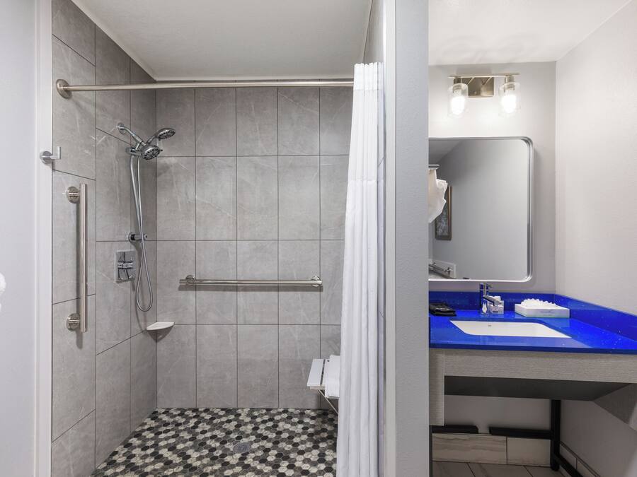 A modern bathroom with a shower, a sink, and a mirror.