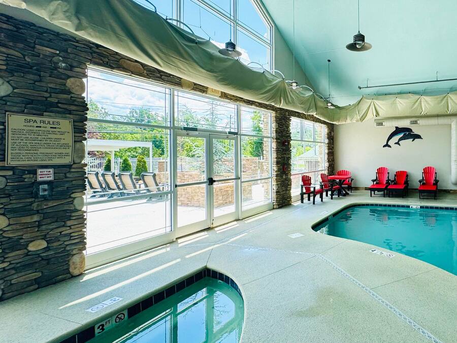 An indoor swimming pool with stone walls, red chairs, and a dolphin mural.