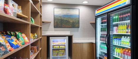 A snack and beverage area with shelves stocked with snacks and a refrigerated display case with various drinks.