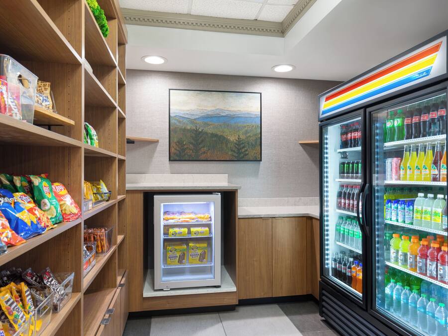 A snack and beverage area with shelves stocked with snacks and a refrigerated display case with various drinks.