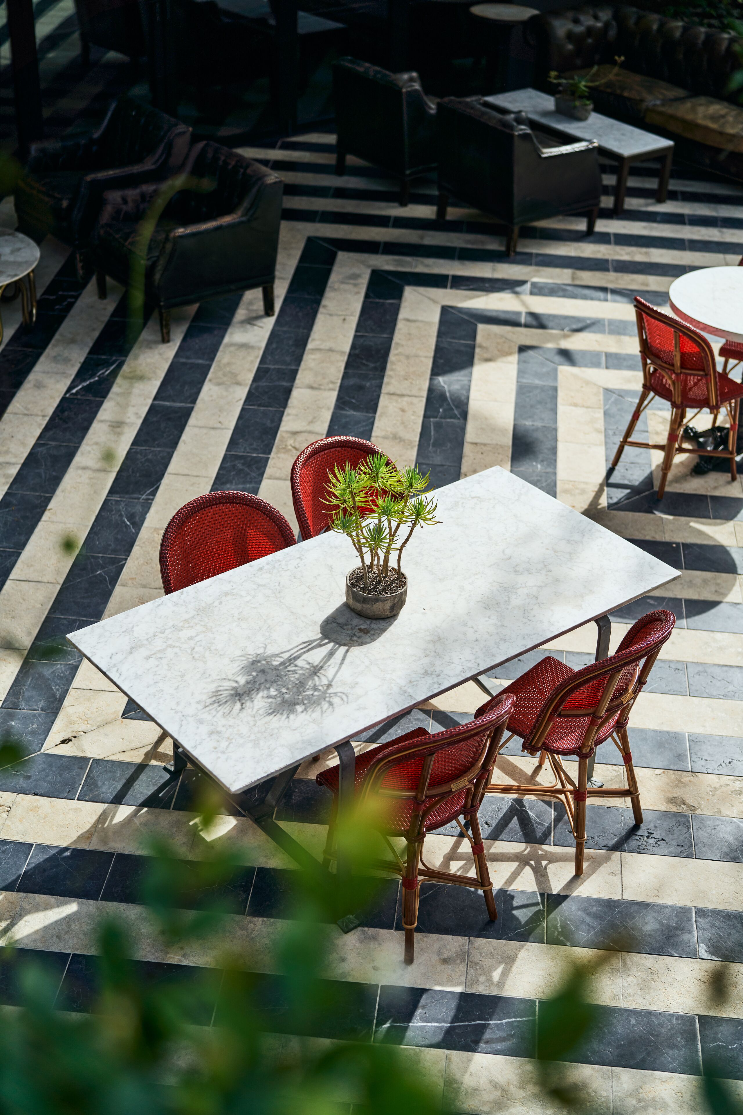 An outdoor patio with a marble table, wicker chairs, and a potted plant.
