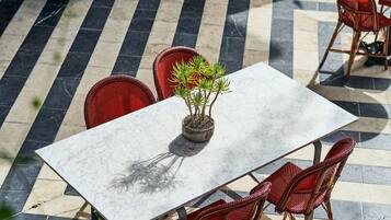 An outdoor patio with a marble table, wicker chairs, and a potted plant.