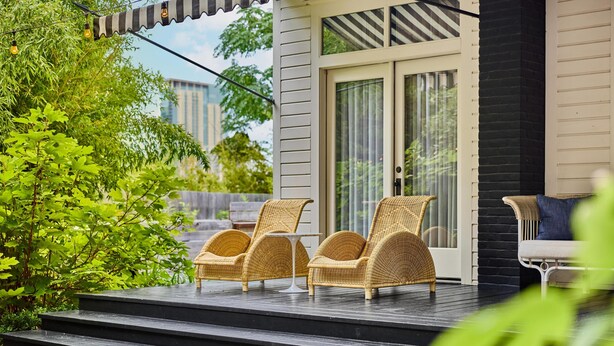 A porch with wicker chairs, a small table, and a bench. - Hotel Saint Cecilia (Austin)