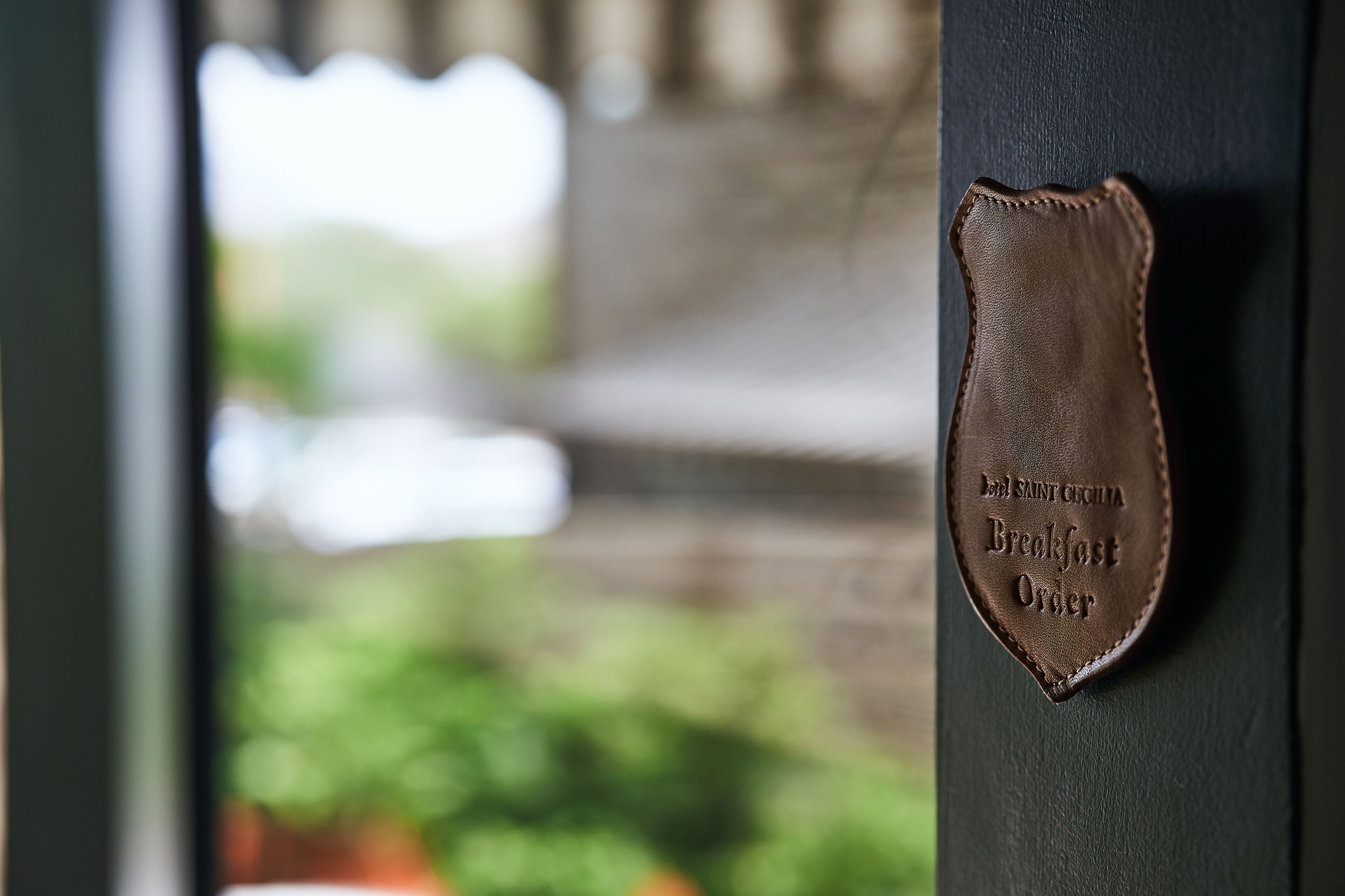 Een lederen plaquette met reliëftekst op een donkere muur.