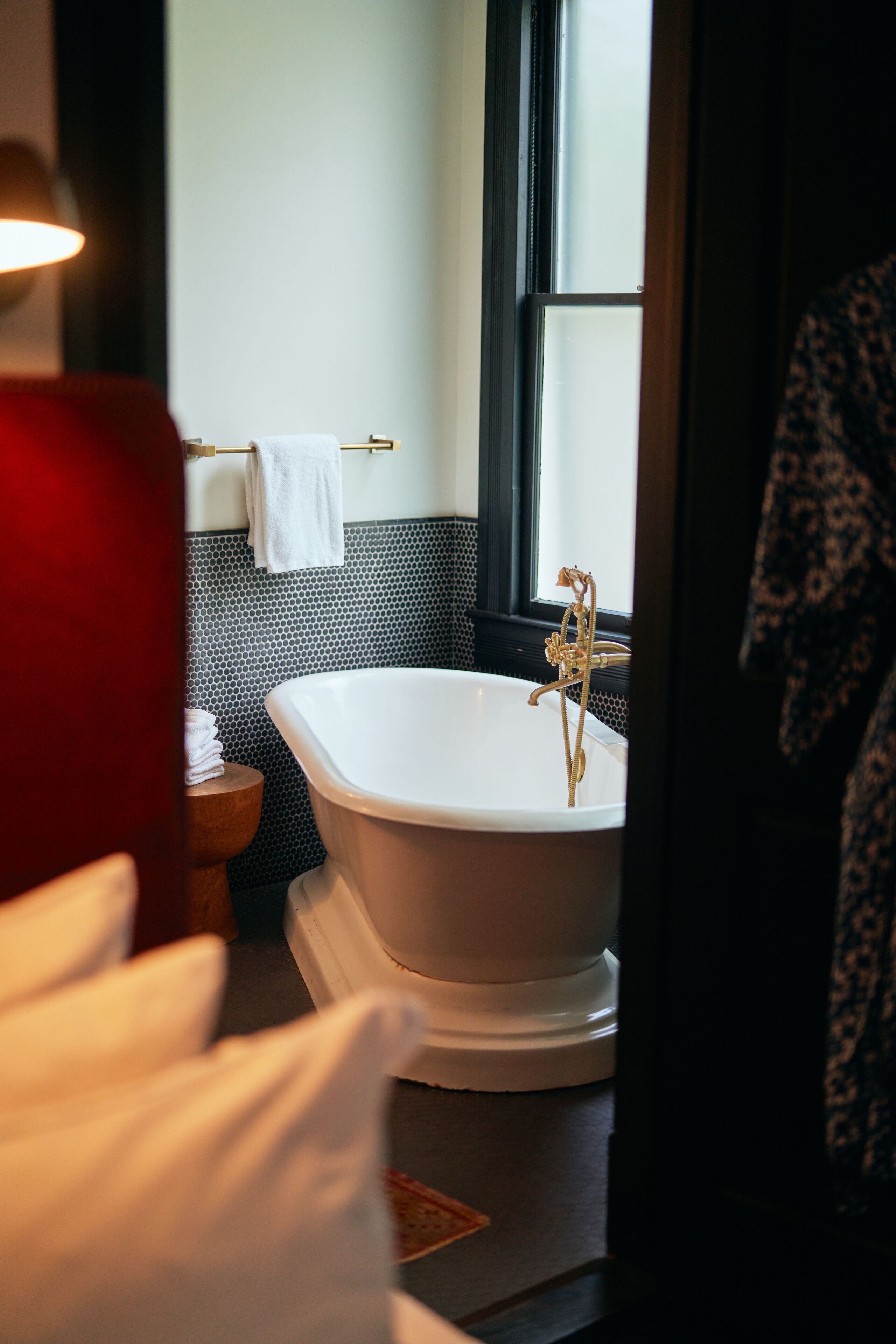 A bathroom with a freestanding bathtub, a towel rack, and a window.