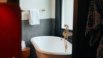 A bathroom with a freestanding bathtub, a towel rack, and a window.