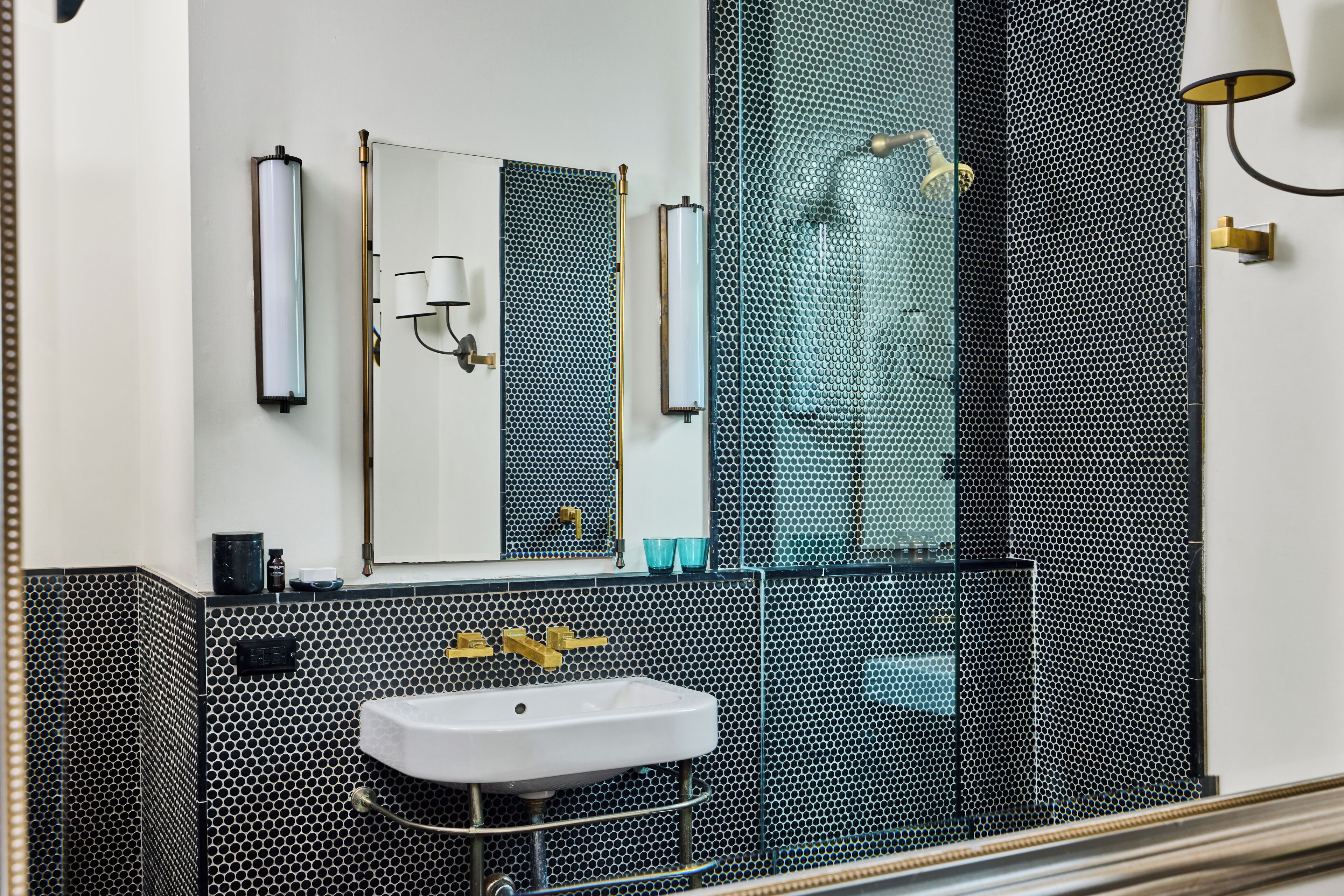 A bathroom with a white sink, a mirror, and a shower with a glass enclosure.