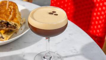 A martini glass with a layered drink on a marble table.