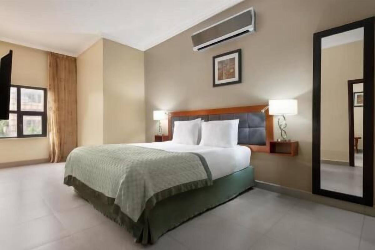 Une chambre d’hôtel équipée d’un lit, de lampes de chevet, d’un grand miroir et d’un appareil de climatisation.