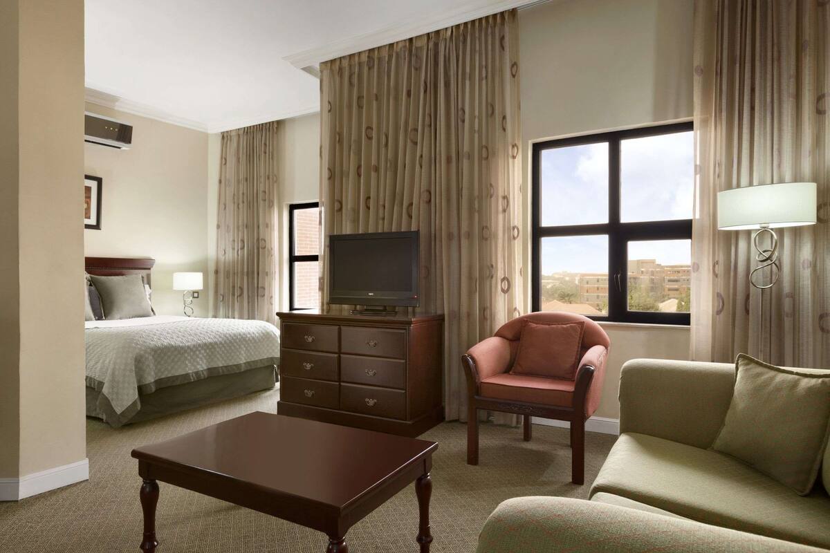 Une chambre d’hôtel équipée d’un lit, d’une télévision, d’un bureau, d’une chaise et d’un canapé.