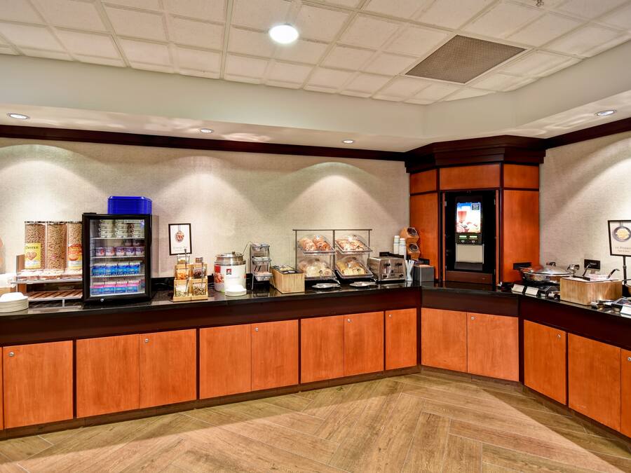 A hotel reception area with a counter displaying various food items and a refrigerator.
