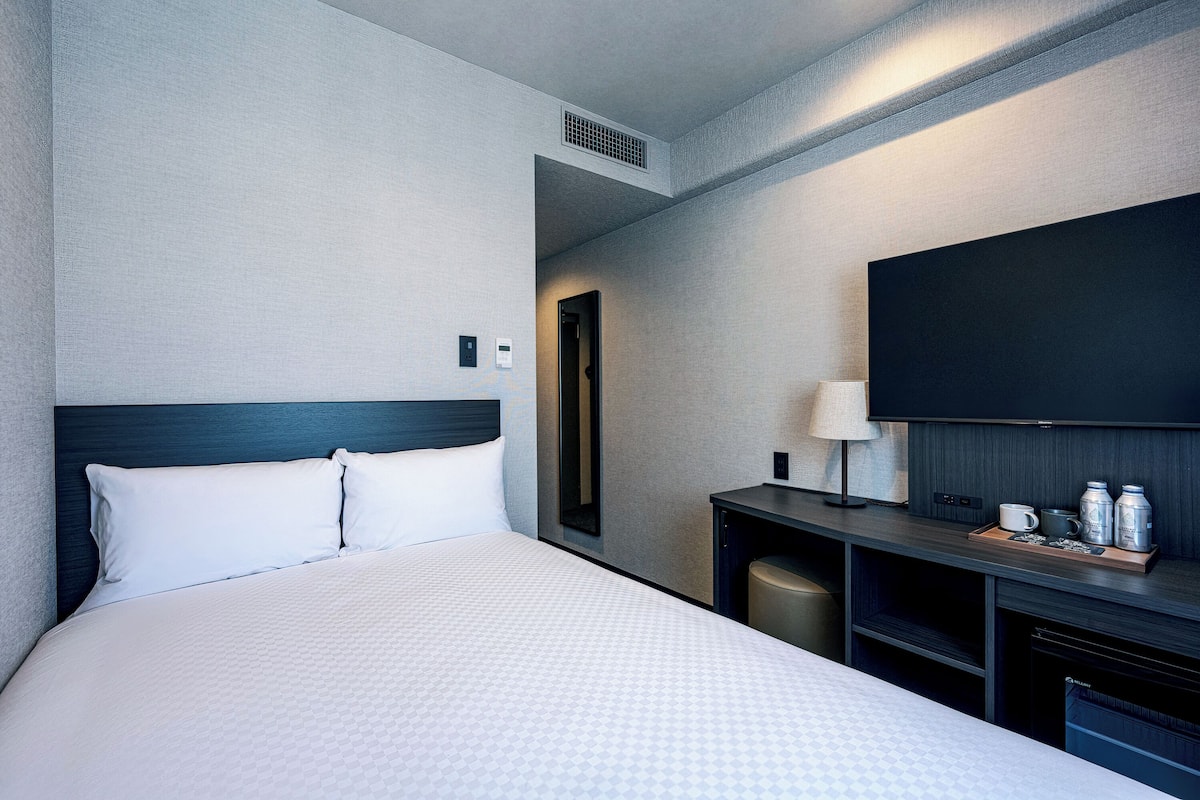 Une chambre d’hôtel équipée d’un lit, d’une télévision, d’un bureau avec une lampe et d’une machine à café.