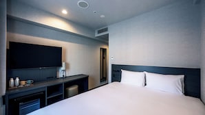 Une chambre d’hôtel avec un grand lit, un téléviseur à écran plat, un bureau avec une lampe et un miroir.
