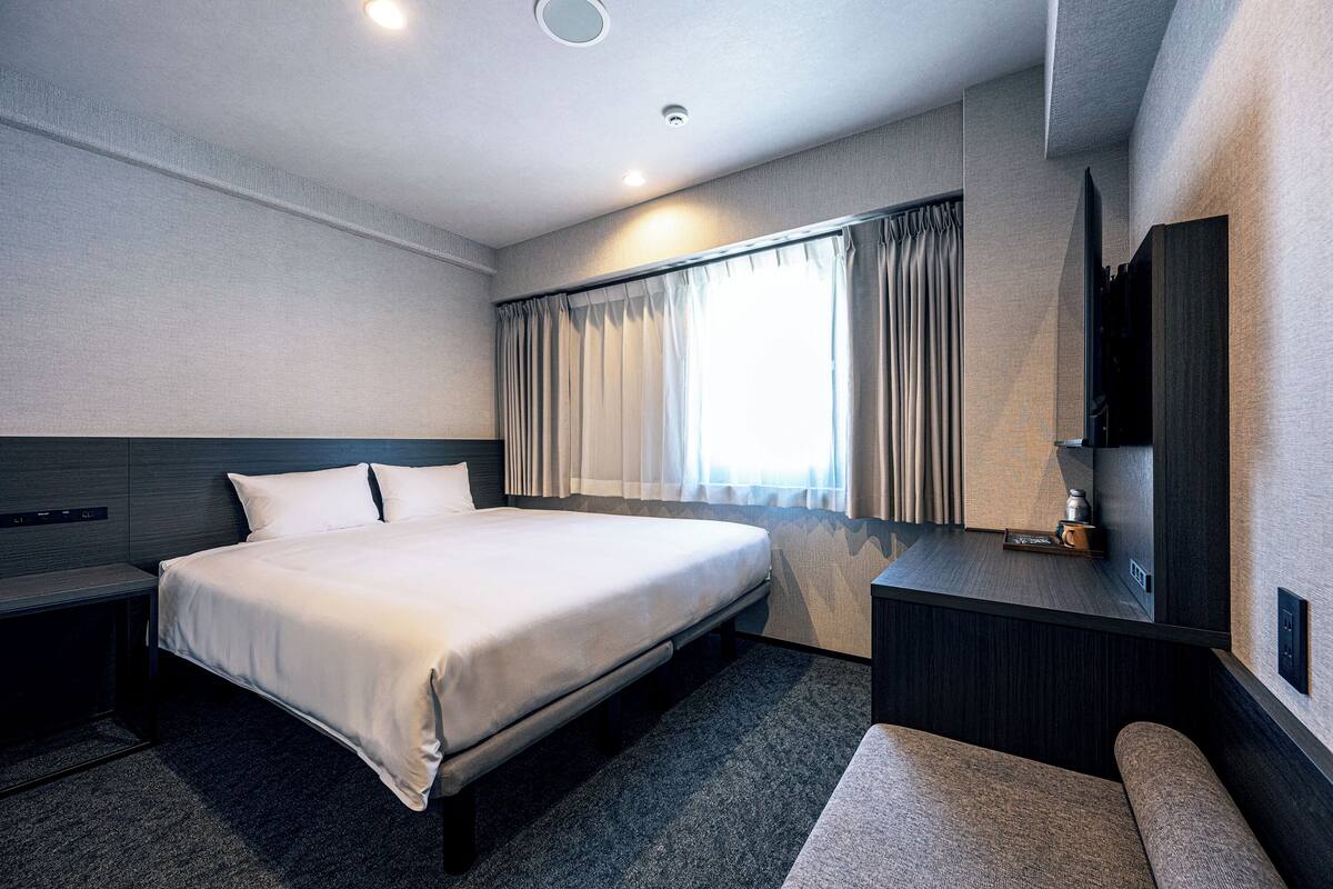 Une chambre d’hôtel moderne, dotée d’un grand lit, d’un bureau et d’une télévision.