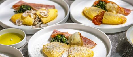 Un menú con diversos platos, incluyendo un plato con tortilla enrollada, otro con jamón y verduras, y un tercero con un guiso de patatas.