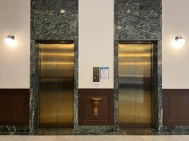 Dos ascensores con paredes de mármol y un panel de control en el centro.