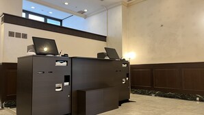 Un comptoir d’accueil équipé de deux ordinateurs, doté d’une grande fenêtre et recouvert d’un sol en marbre.