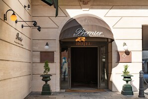 De ingang van het Premier Plaza Hotel, met een grote boog, een bord boven de deur en twee plantenpotten aan weerszijden.