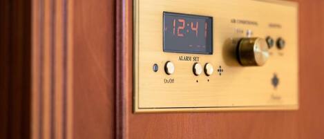 Panel de madera con un reloj digital que muestra las 12:41, un botón para configurar la alarma y perillas de control.