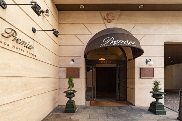 De ingang van Premier Plaza Hotel Premier, met een klassieke gebogen entree en een bord boven de deur.