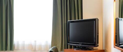 Une chambre d’hôtel avec un lit, un bureau avec une télévision et une lampe.