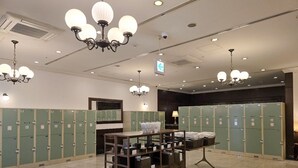 Une salle de bain d’hôtel équipée de plusieurs casiers, d’une coiffeuse avec un miroir et d’une table centrale agrémentée de paniers et de serviettes.