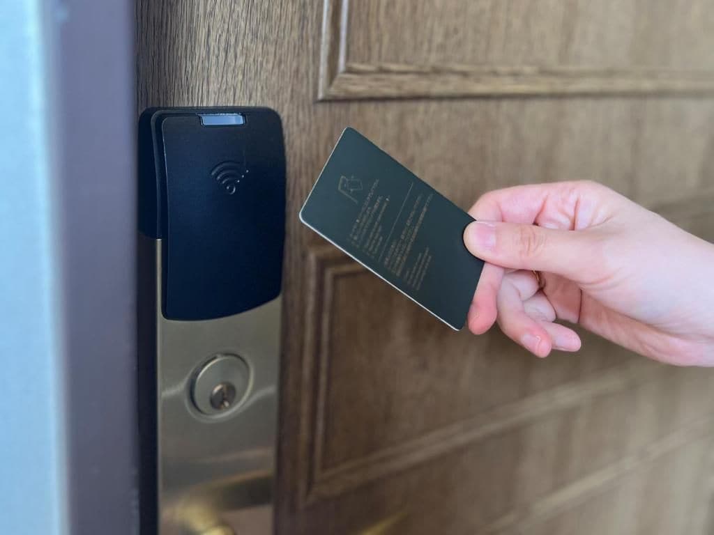 A hand holding a card near a door lock mechanism.