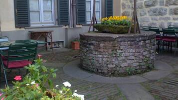 An outdoor seating area with stone tables and chairs, a flower planter, and a stone wall.